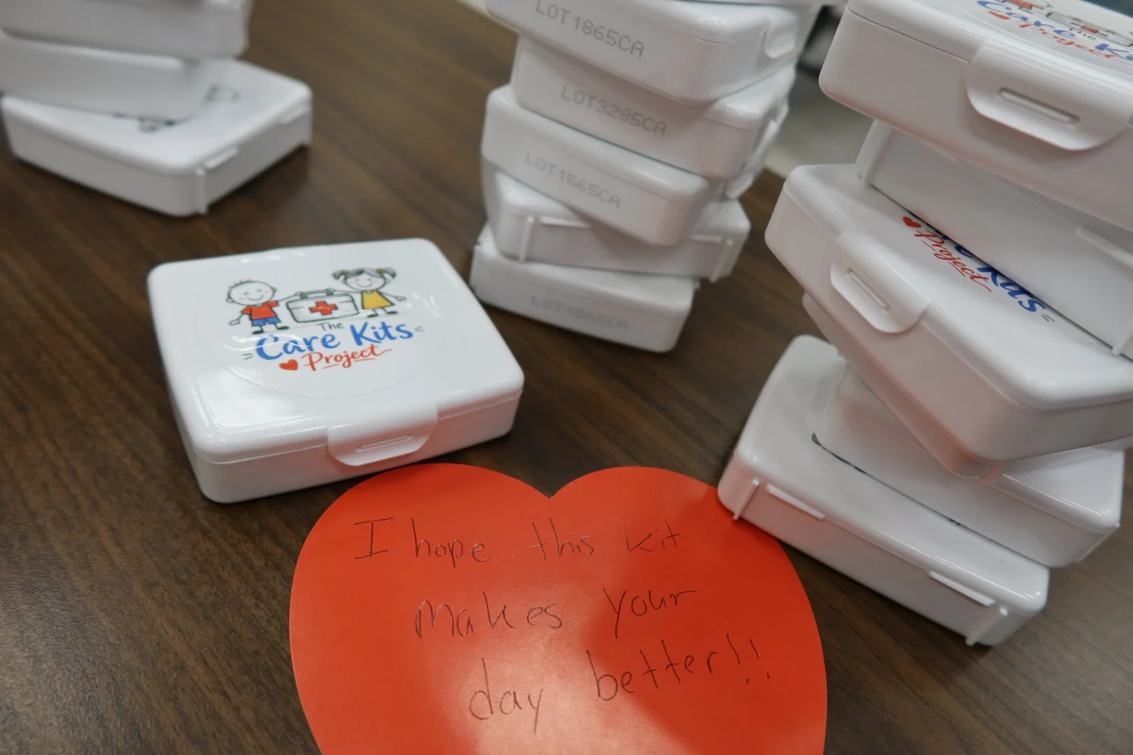 Stacked finished care kit cases with a heart-shaped note