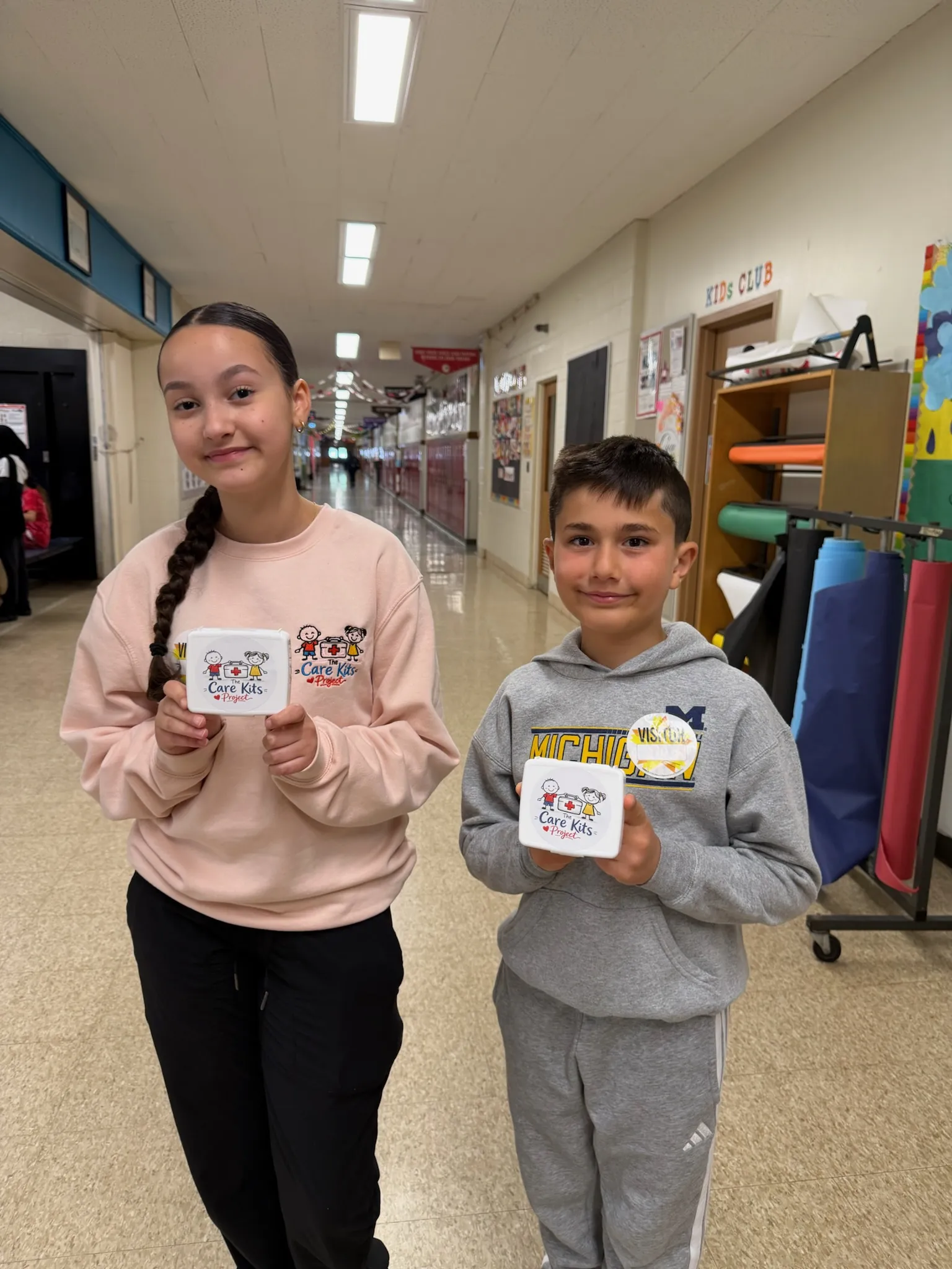 Two students showing off their care kits in the school hallway