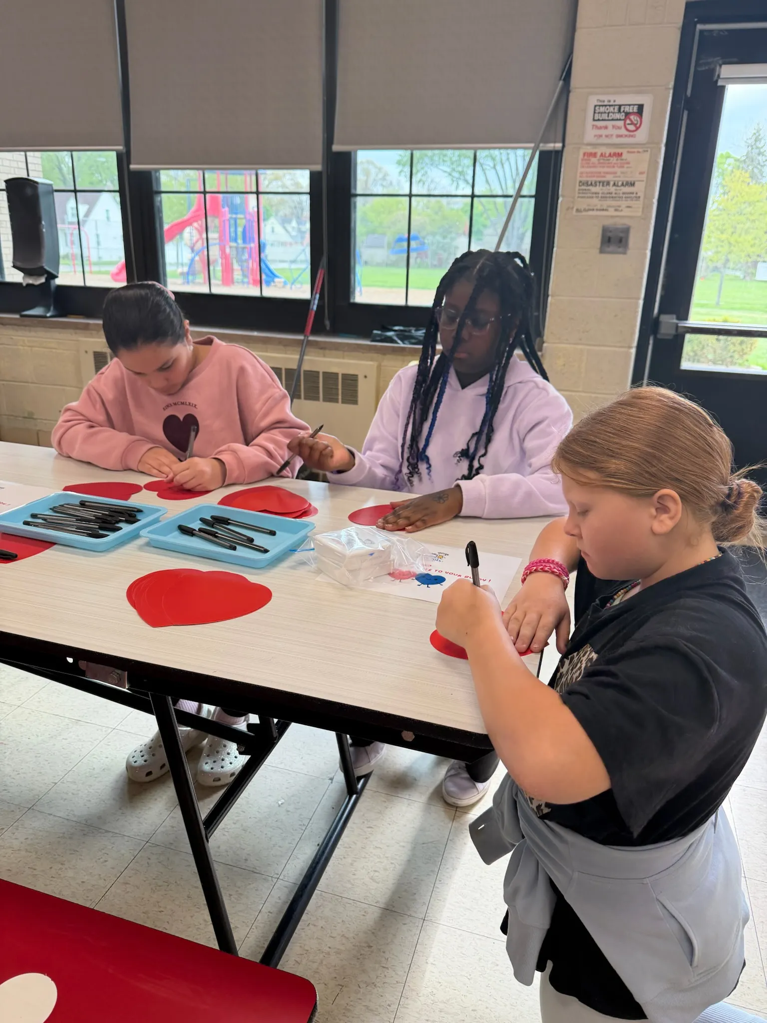 Students writing heart notes at a workshop table