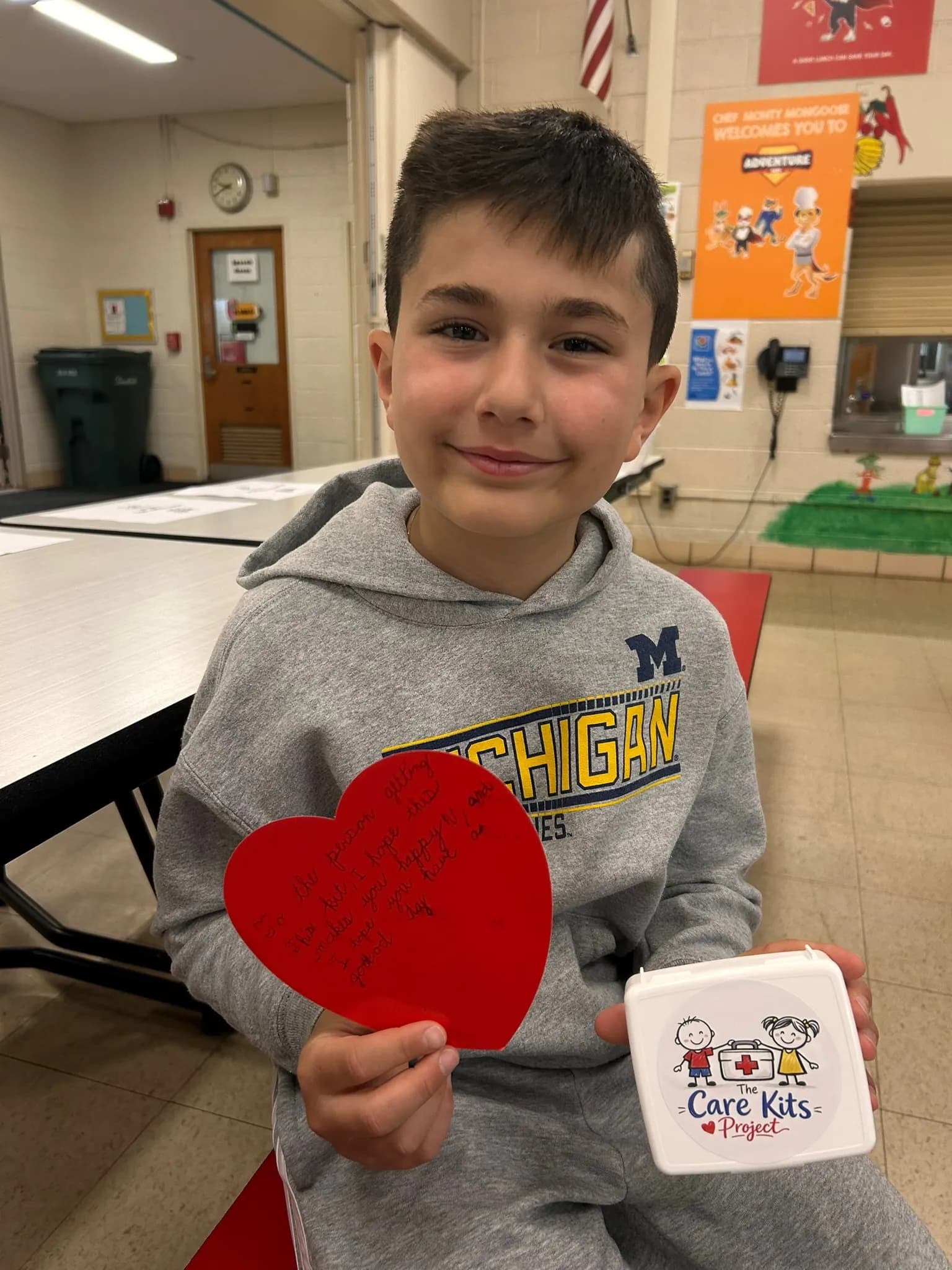 A student holding a handwritten heart-shaped note and his care kit